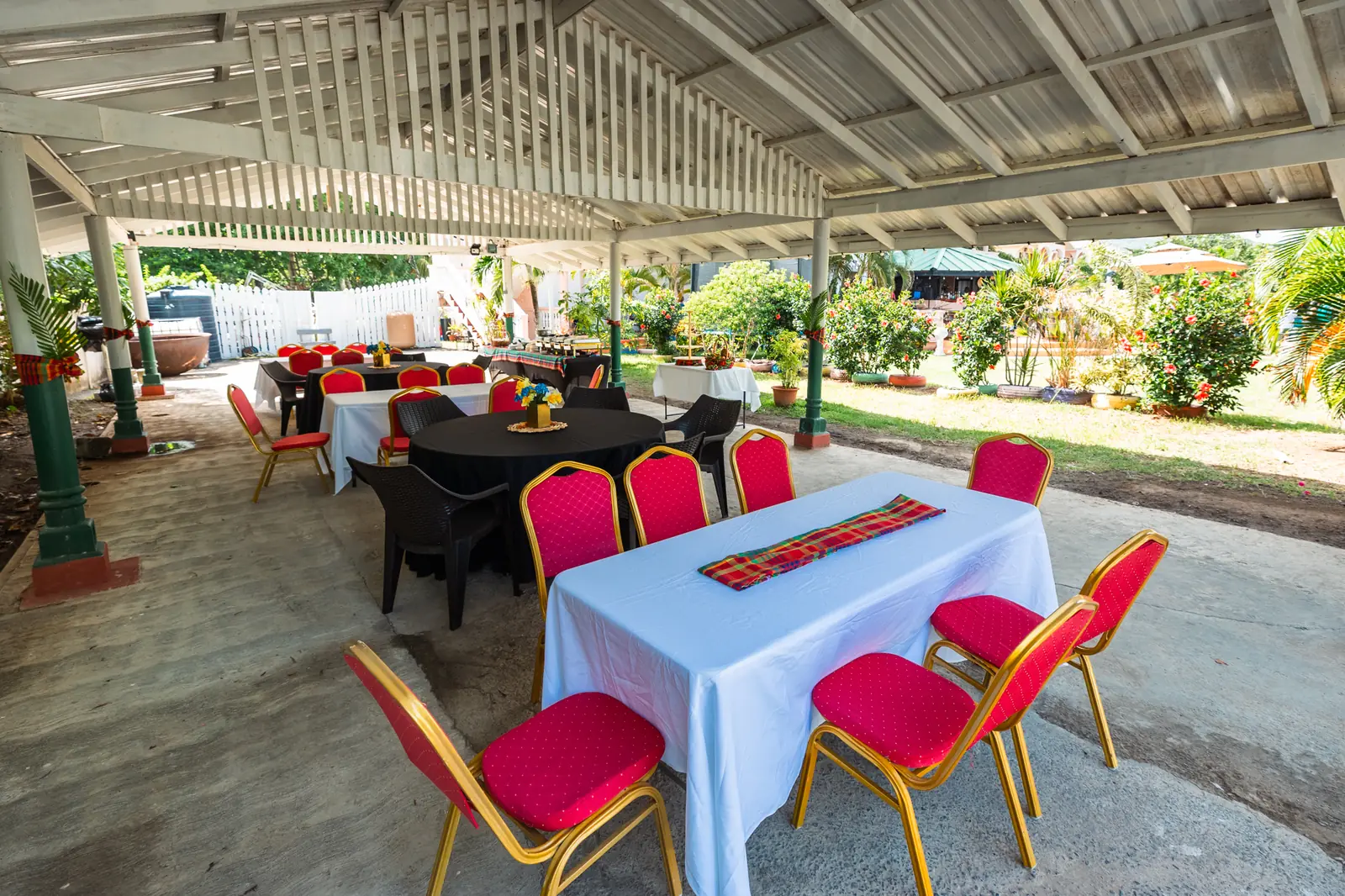 Covered pavilion at Hewanorra Gardens set with tables, linens and red chairs for an event