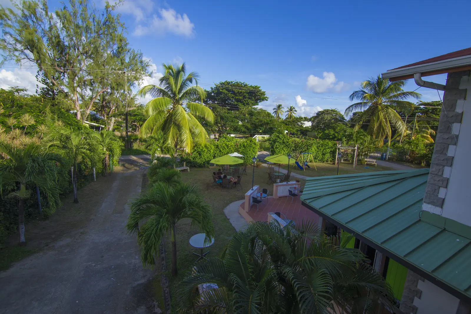 View over the palm-filled gardens, lawn and patio of Hewanorra Gardens under a blue sky