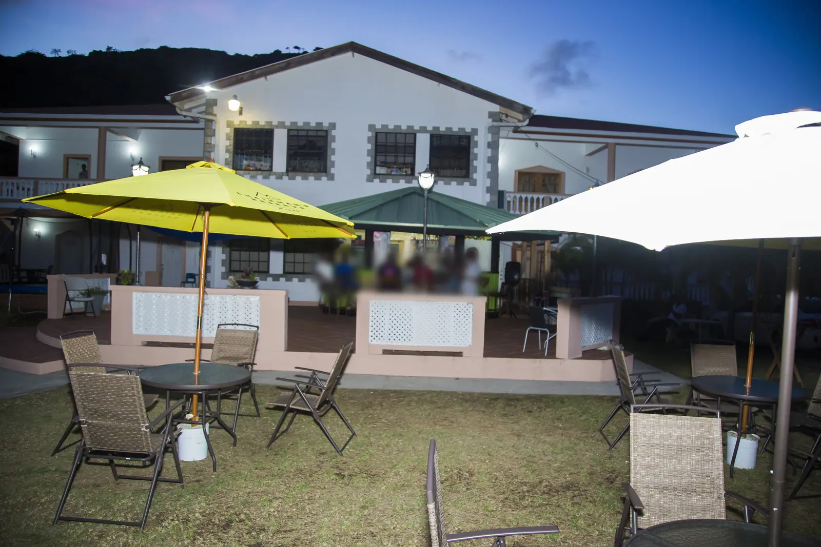 The garden lawn with umbrellas and the main guesthouse at dusk